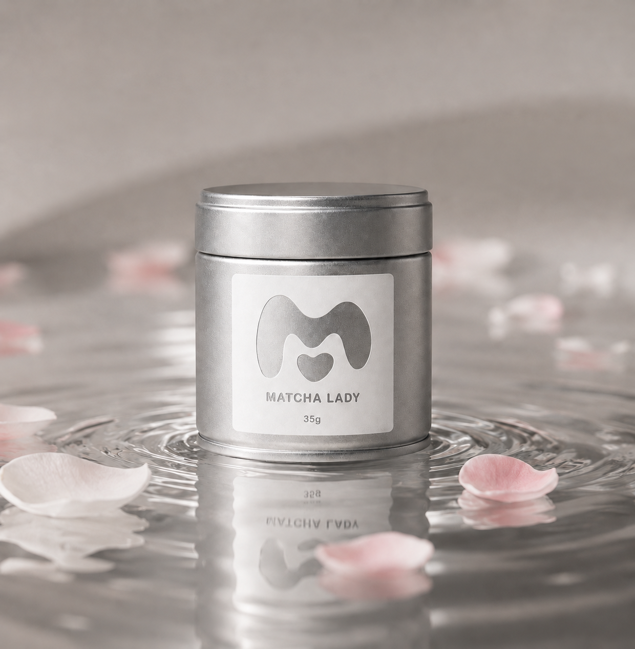 35g Matcha Lady tin reflected in water with floating petals